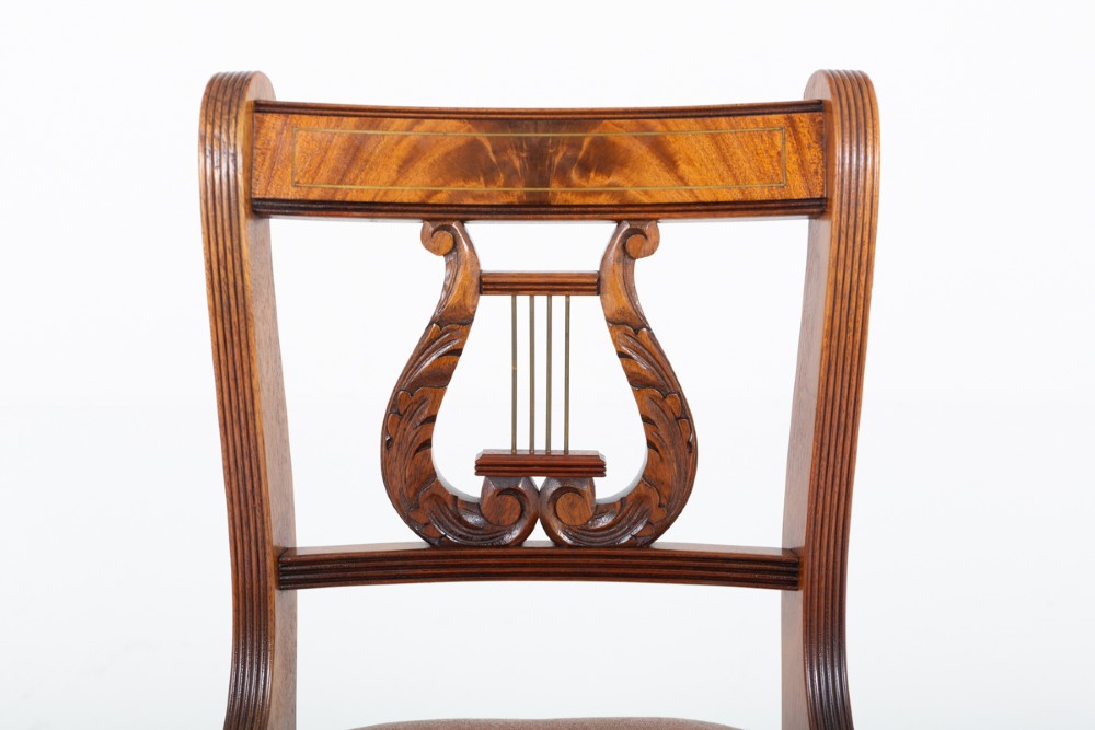 A set of ten mahogany Regency style dining chairs featuring carved lyre back splats, curved armrests on two carvers, and rust-coloured upholstered seats. View IX