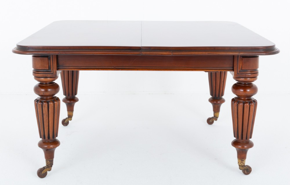 A William IV mahogany extending dining table with three additional leaves, standing on turned and reeded legs with brass castors. View II