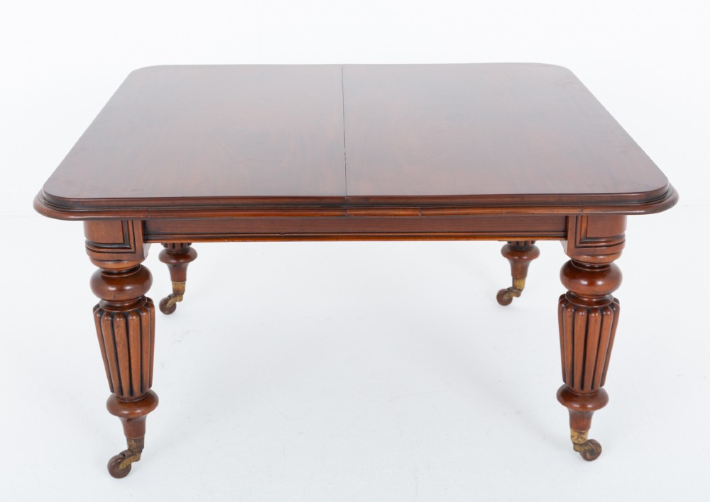 A William IV mahogany extending dining table with three additional leaves, standing on turned and reeded legs with brass castors. View III
