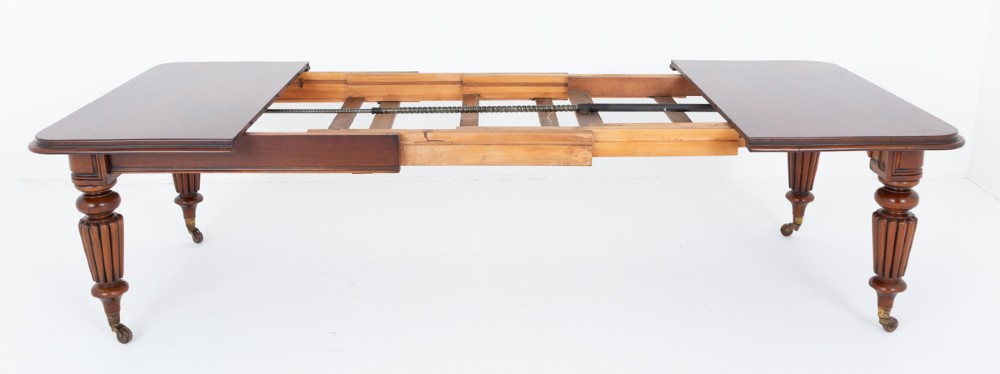 A William IV mahogany extending dining table with three additional leaves, standing on turned and reeded legs with brass castors. View VI