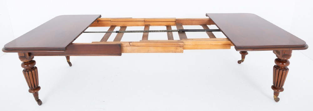 A William IV mahogany extending dining table with three additional leaves, standing on turned and reeded legs with brass castors. View VII