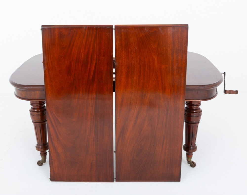 A Victorian mahogany extending dining table with two removable extension leaves, turned fluted legs, and brass castors. View XI