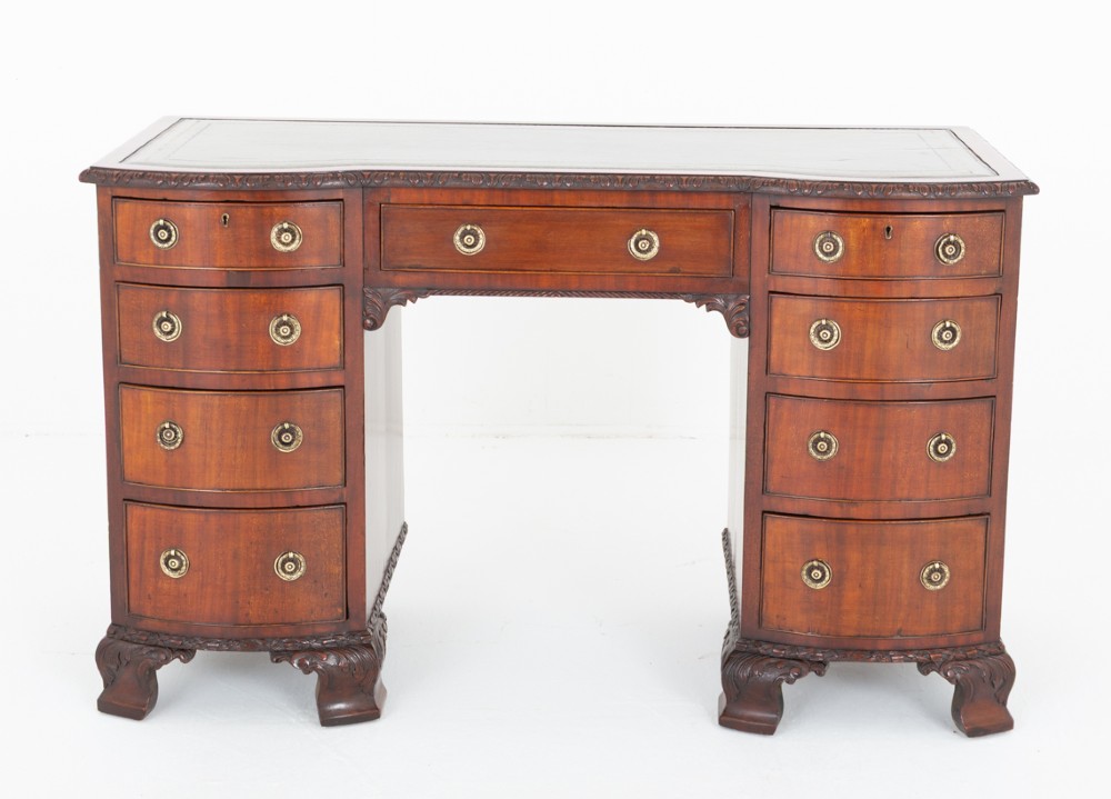 A Georgian Revival mahogany pedestal desk featuring a leather-lined top, curved drawer fronts with brass ring handles, and carved bracket feet. View III