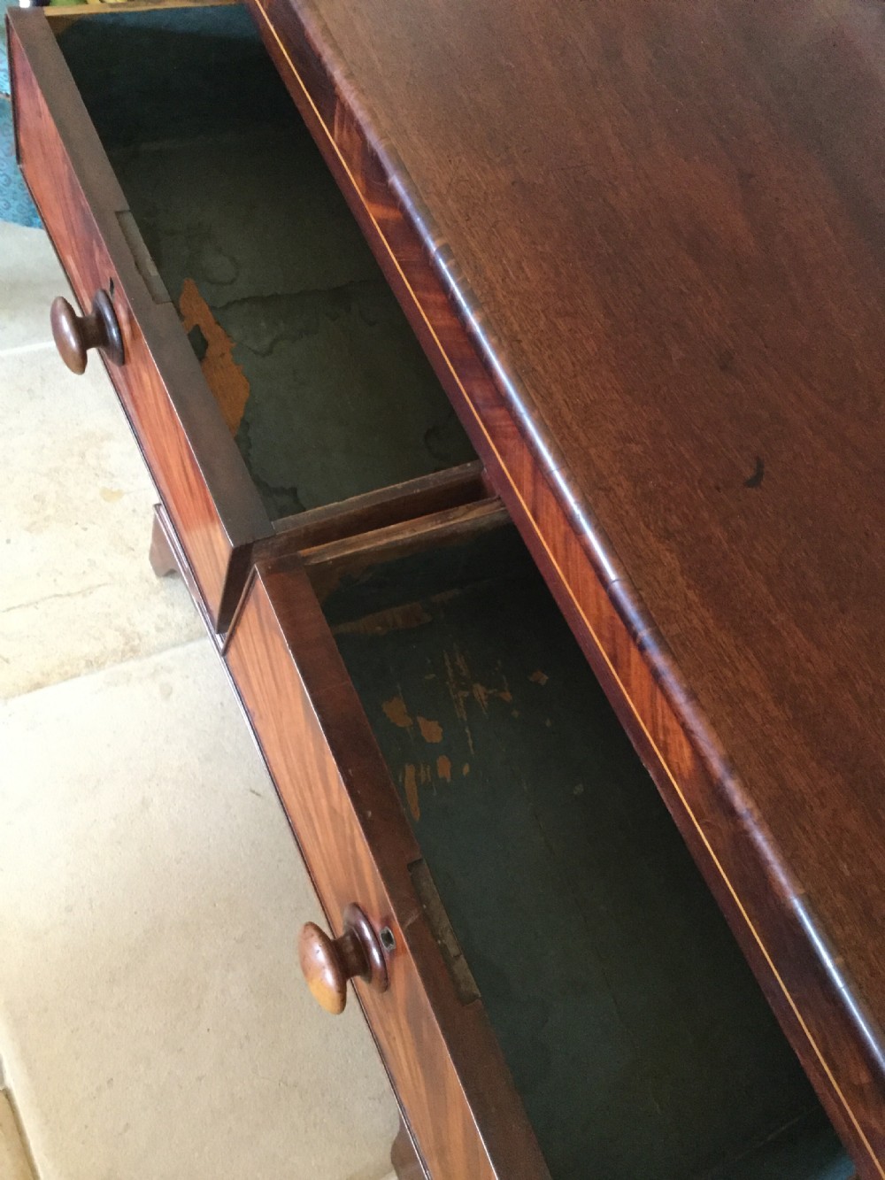 A Victorian mahogany chest of drawers featuring flame mahogany veneer fronts, turned handles, and a two-short-over-three-long drawer layout on bracket feet. View XI