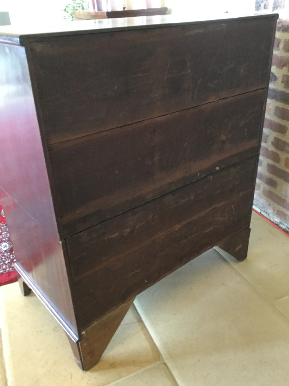 A Victorian mahogany chest of drawers featuring flame mahogany veneer fronts, turned handles, and a two-short-over-three-long drawer layout on bracket feet. View XII