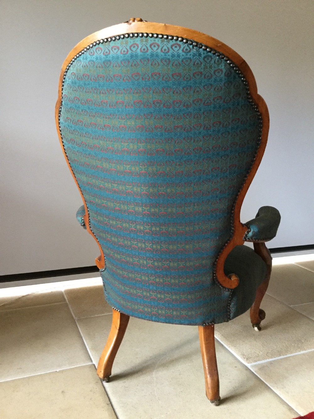 A Victorian carved walnut open armchair upholstered in patterned teal fabric with cabriole legs and front castors. View VII