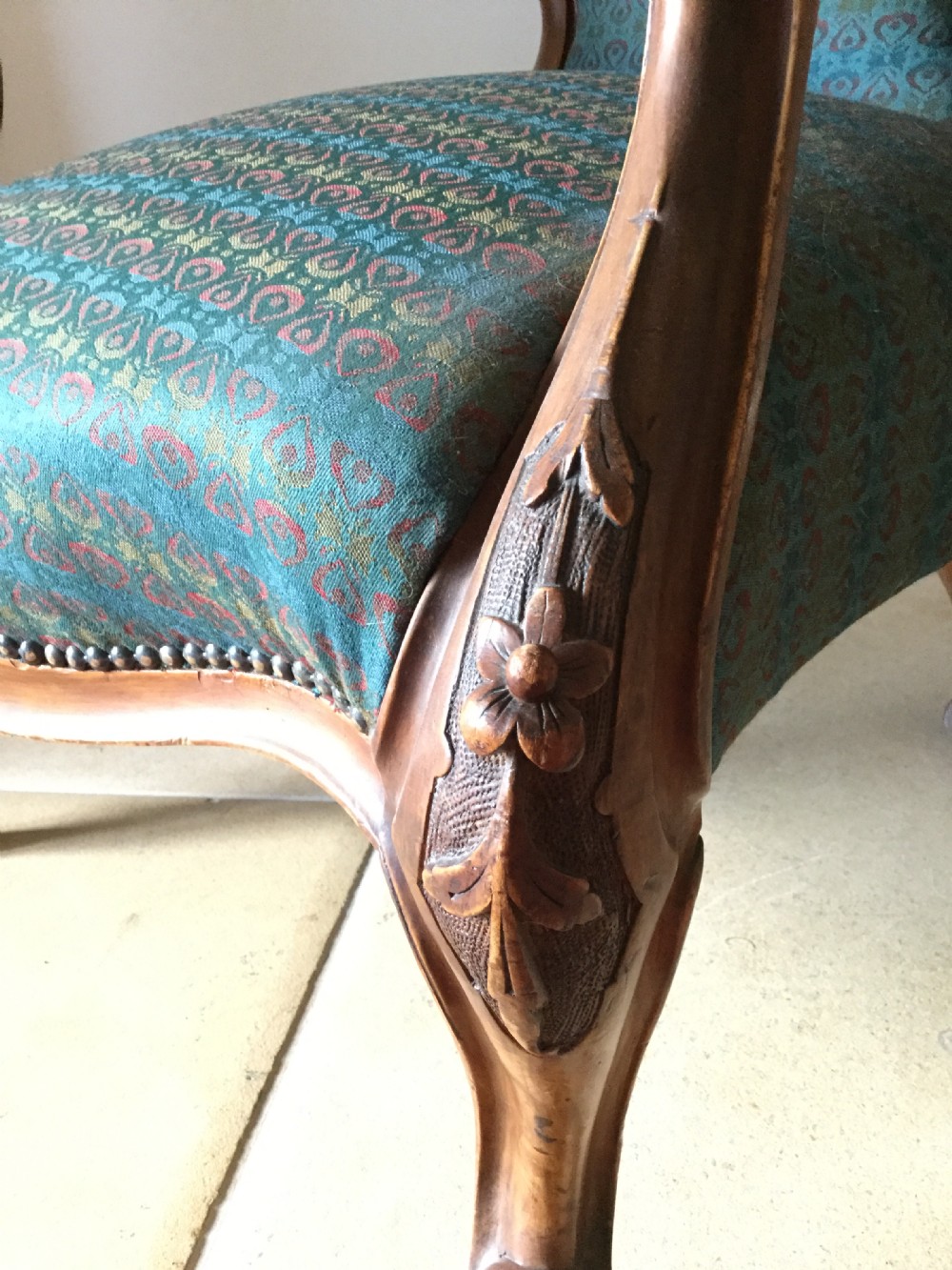 A Victorian carved walnut open armchair upholstered in patterned teal fabric with cabriole legs and front castors. View IX