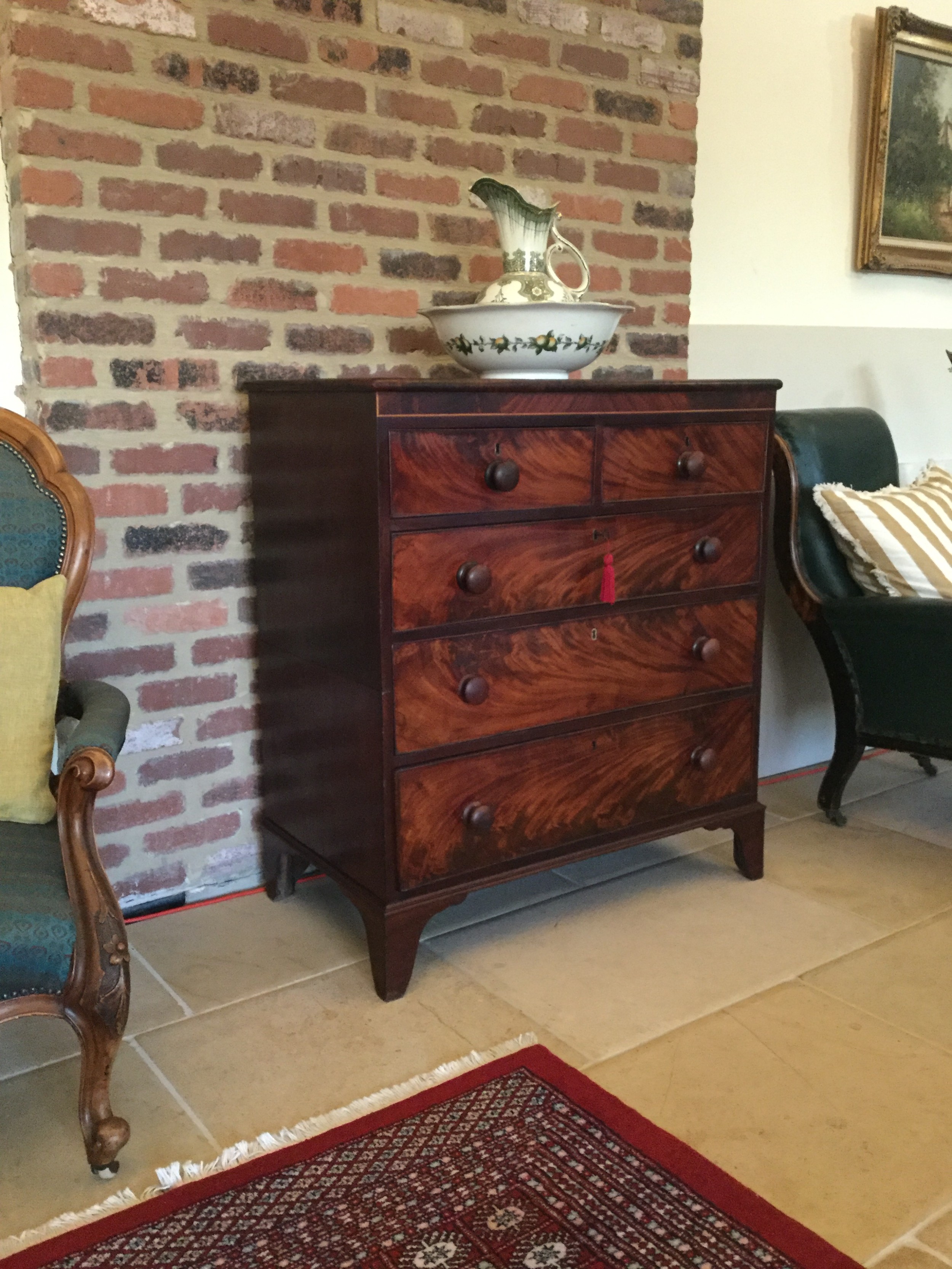 A Victorian mahogany chest of drawers featuring flame mahogany veneer fronts, turned handles, and a two-short-over-three-long drawer layout on bracket feet.