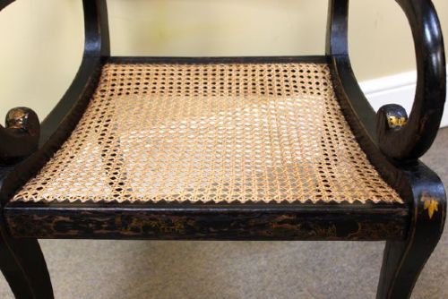 A pair of ebonised Regency armchairs featuring woven cane seats and backrests, swept armrests, and front sabre legs. View II
