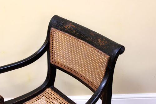 A pair of ebonised Regency armchairs featuring woven cane seats and backrests, swept armrests, and front sabre legs. View III