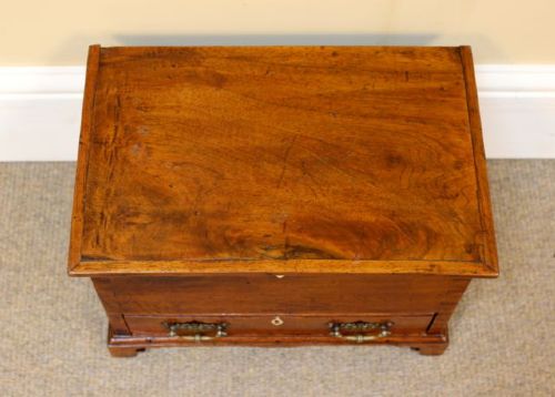 A 19th-century miniature walnut mule chest featuring visible dovetail joinery, a hinged top lid, a single lower drawer with decorative brass handles, and bone keyhole escutcheons. View V