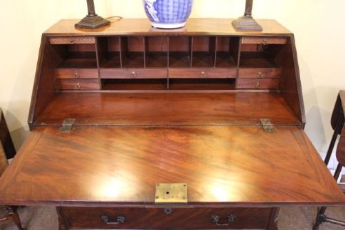 An 18th-century Georgian flame mahogany bureau featuring a sloping fall-front lid, four graduated drawers with brass handles, and ogee bracket feet. View IV
