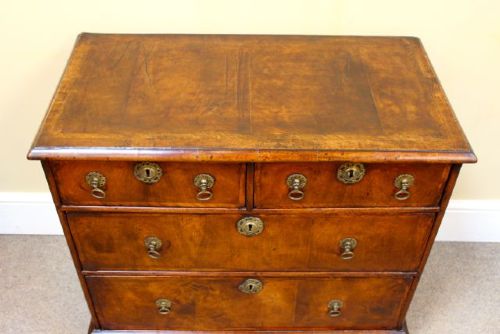 An 18th-century Georgian walnut chest of drawers featuring two short over two long drawers with brass drop handles and bracket feet. View V