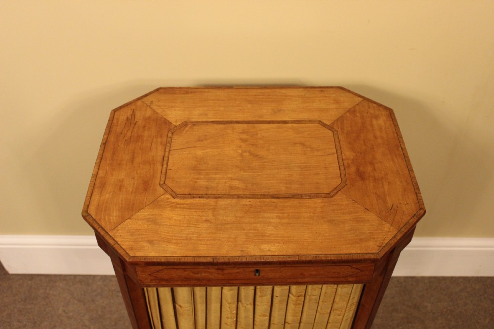 A nineteenth-century golden satinwood work table featuring a hinged octagonal top, line inlay details, a pleated fabric basket beneath, and tapered legs connected by an X-stretcher. View IV