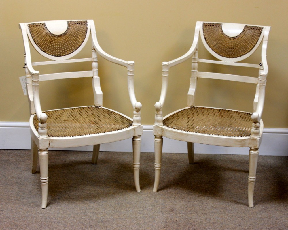 A pair of off-white painted Regency armchairs featuring hand-woven cane seats, crescent caned backrests, and turned front legs. View II