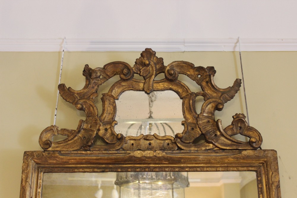 A large rectangular antique wall mirror featuring an ornate carved giltwood frame with a scrolled pierced cresting and carved apron. View III