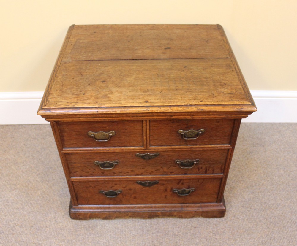 An 18th-century dark oak close stool featuring a hinged lid, brass swan-neck handles, faux drawer fronts, and a bracket base. View II
