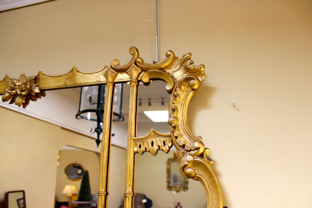 A horizontal 19th-century giltwood overmantel mirror featuring carved floral cresting, vertical column supports, and geometric fretwork along the base. View V