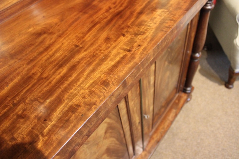 A nineteenth-century mahogany chiffonier featuring a upper shelf gallery on turned supports above a two-door cabinet with flame mahogany veneer panels. View V
