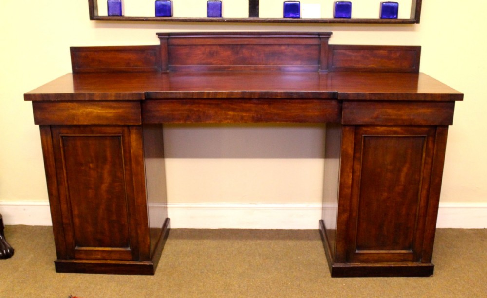 A nineteenth-century mahogany pedestal sideboard featuring twin cupboard bases, a recessed central drawer section, and a stepped backboard.