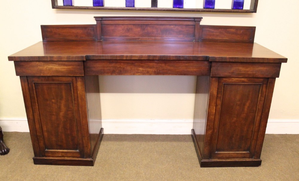 A nineteenth-century mahogany pedestal sideboard featuring twin cupboard bases, a recessed central drawer section, and a stepped backboard. View II