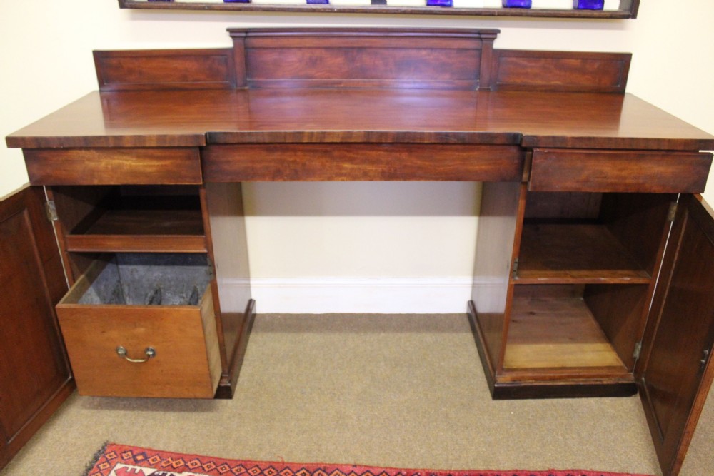 A nineteenth-century mahogany pedestal sideboard featuring twin cupboard bases, a recessed central drawer section, and a stepped backboard. View IV