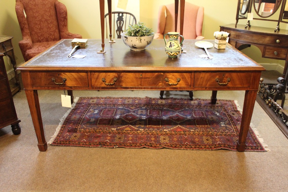 A rectangular mahogany partners desk with a dark leather top, multiple drawers with brass handles, and square tapered legs. View II