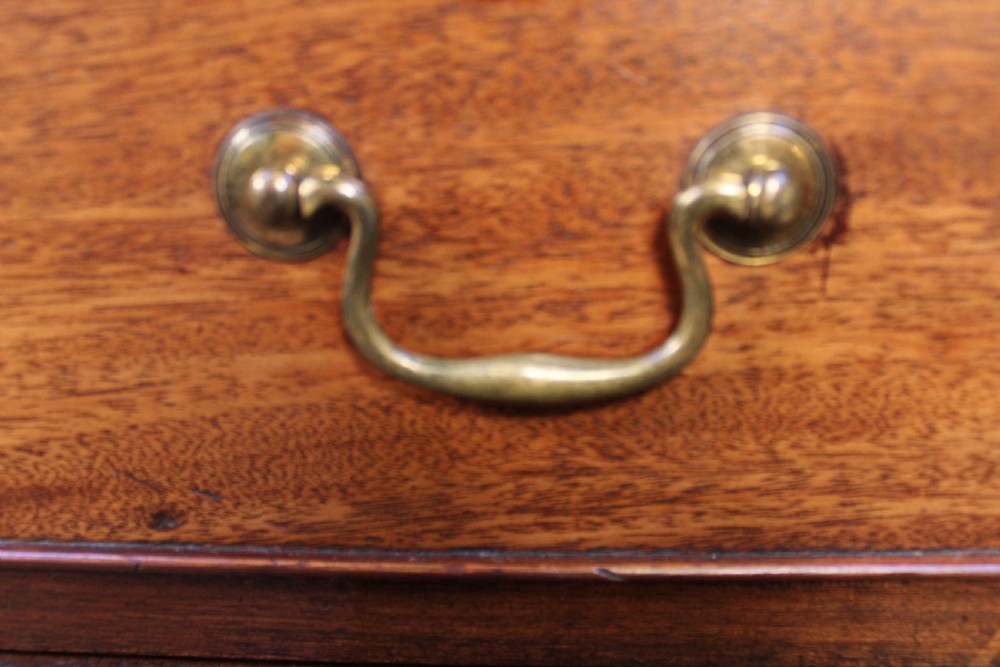 A 19th-century mahogany chest of drawers with four graduated drawers, brass swan-neck handles, escutcheons, and bracket feet. View V