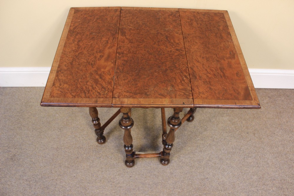 A nineteenth-century amboyna and walnut occasional table featuring rich burr graining, a rectangular top, and turned legs joined by a cross-stretcher. View V