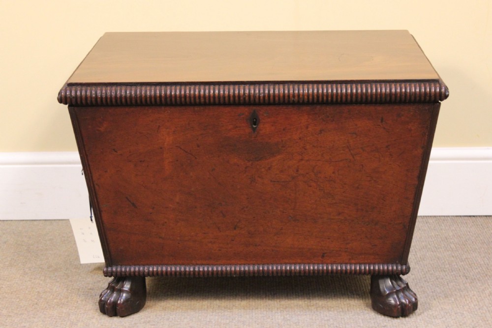 A nineteenth-century mahogany sarcophagus-shaped cellarette featuring reeded moulding borders, a keyhole escutcheon, and carved paw feet.
