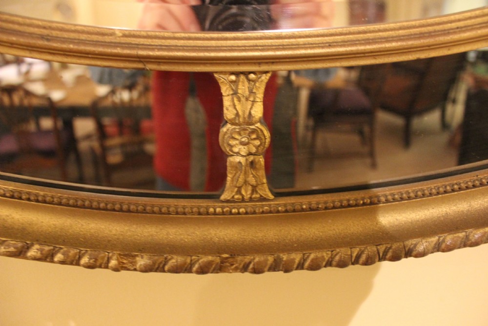 A horizontal 19th-century oval wall mirror featuring a gilded dual-ring frame connected by decorative spoke-like rosettes. View IV