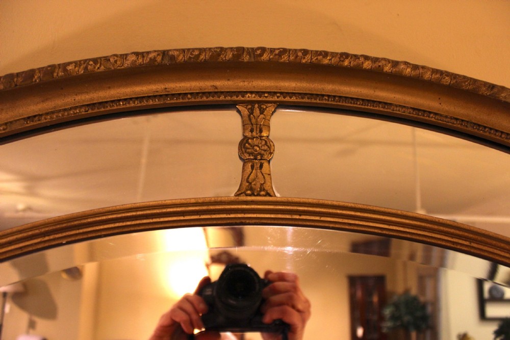 A horizontal 19th-century oval wall mirror featuring a gilded dual-ring frame connected by decorative spoke-like rosettes. View V