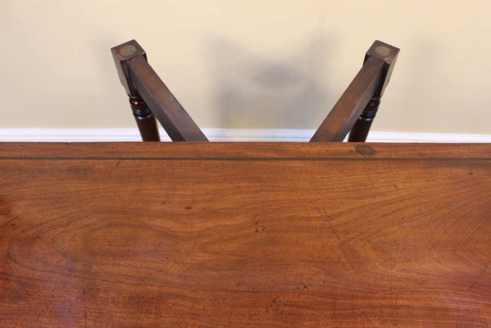 An early 19th-century mahogany fold-over card table featuring a shaped top, flame mahogany veneers, and fluted tapered legs adorned with carved rosettes. View VI