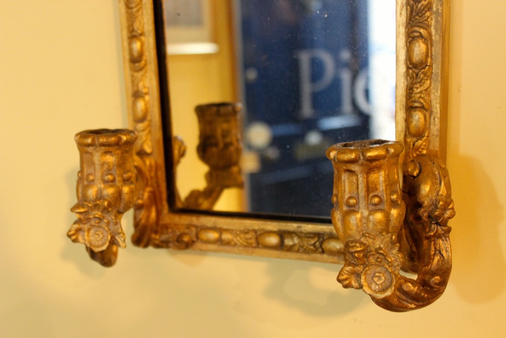A pair of late nineteenth-century arched gilt wall mirrors featuring egg-and-dart moulding and integrated twin candle sconces at the base. View IV