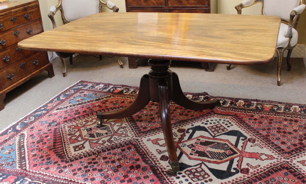 A 19th-century mahogany breakfast table with a rectangular top, rounded corners, and a central pedestal supported by four curved legs on brass castors. View III