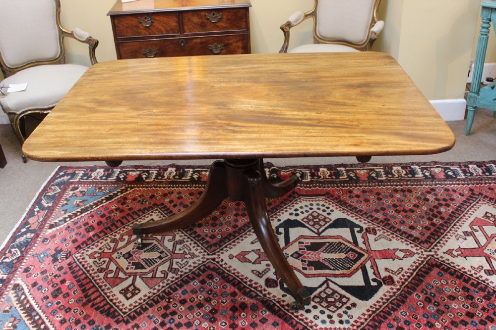 A 19th-century mahogany breakfast table with a rectangular top, rounded corners, and a central pedestal supported by four curved legs on brass castors. View IV