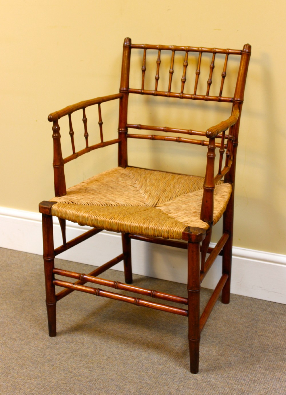 An early 19th century armchair featuring hand-turned faux bamboo framing and a woven rush seat.