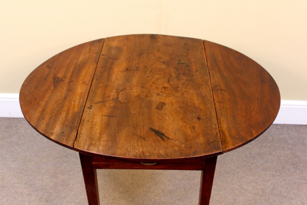 A rectangular Georgian mahogany Pembroke table featuring two drop leaves and tapered legs stands against a neutral background. View V