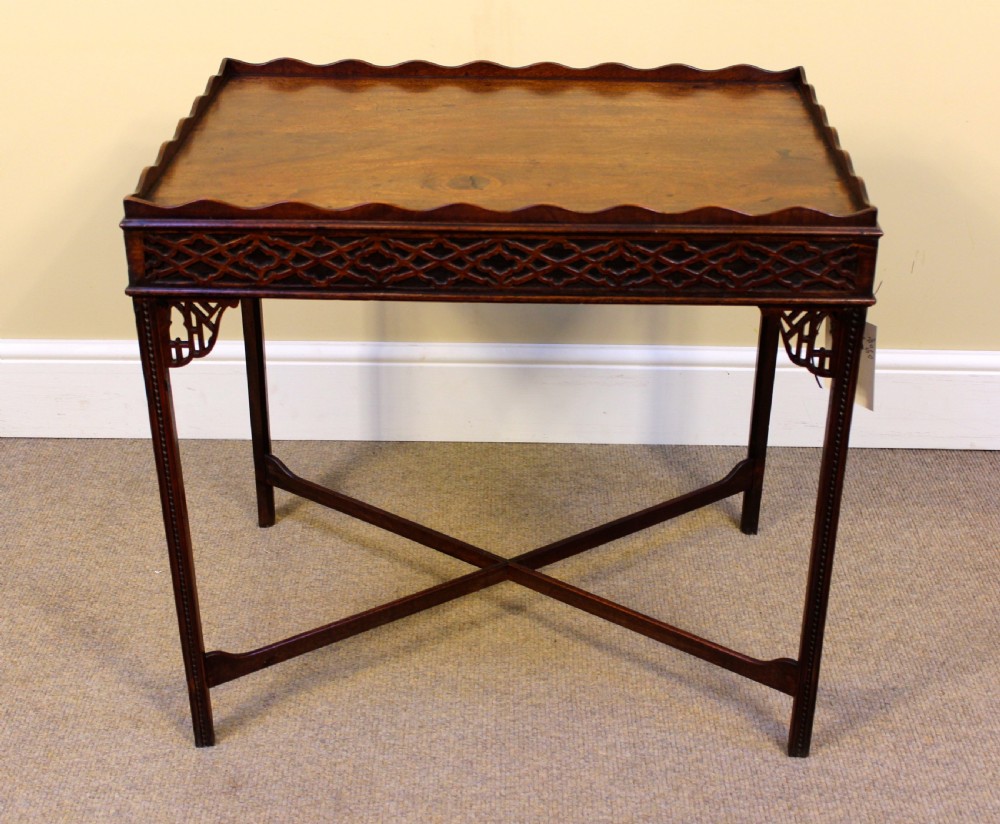 A late 18th-century mahogany silver table featuring a scalloped gallery rim, carved fretwork apron, corner brackets, and an X-shaped stretcher joining four straight legs.