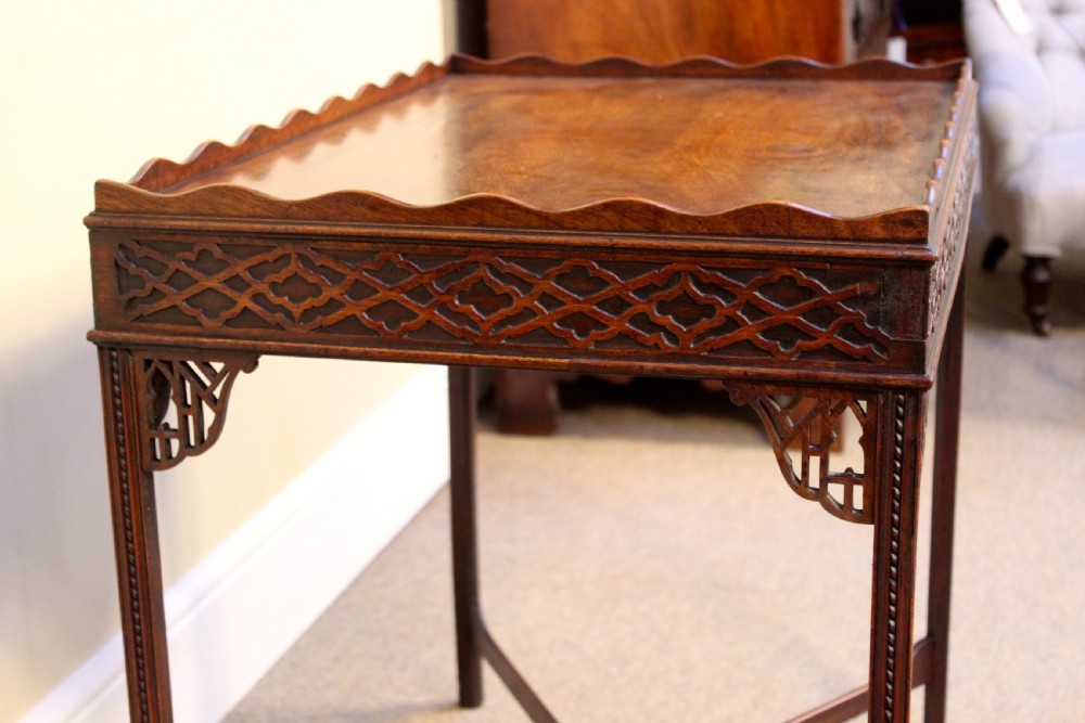 A late 18th-century mahogany silver table featuring a scalloped gallery rim, carved fretwork apron, corner brackets, and an X-shaped stretcher joining four straight legs. View IV