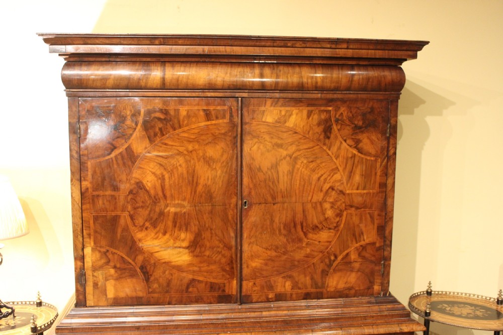 An 18th-century walnut cabinet on stand featuring double doors with circular veneer patterning, two frieze drawers, and barley twist legs united by a wavy stretcher. View II