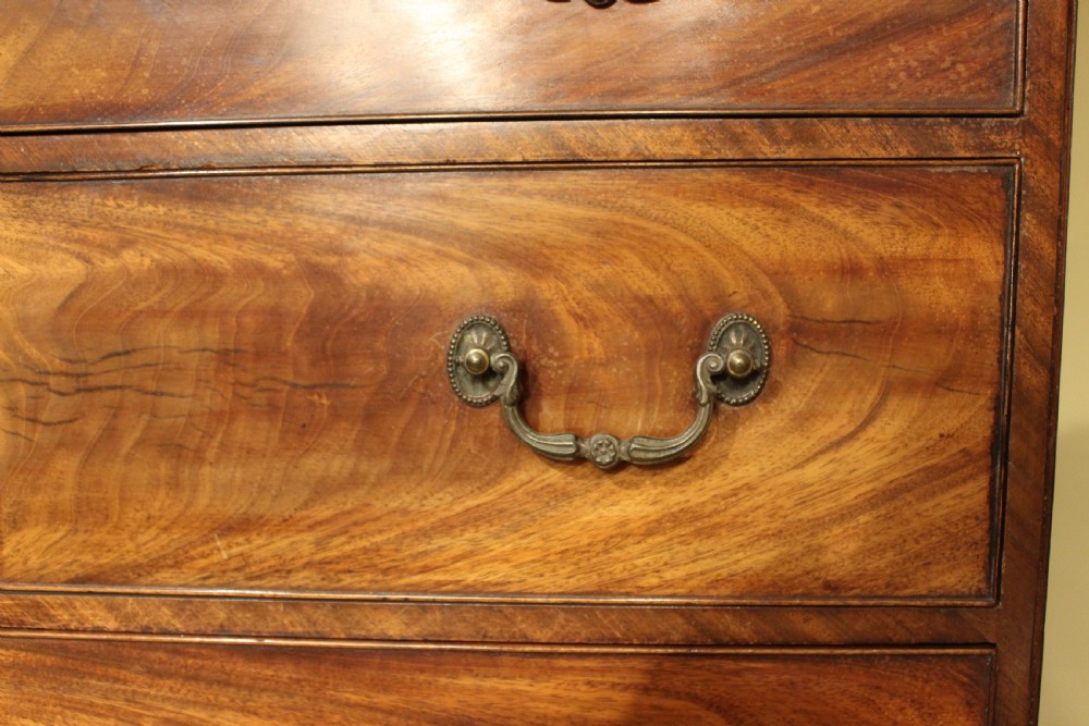 A late 18th-century mahogany secretaire chest on chest featuring flame mahogany veneer, brass swan-neck handles, a decorative blind-fret cornice, and bracket feet. View II