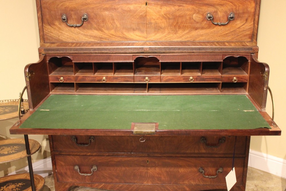 A late 18th-century mahogany secretaire chest on chest featuring flame mahogany veneer, brass swan-neck handles, a decorative blind-fret cornice, and bracket feet. View III