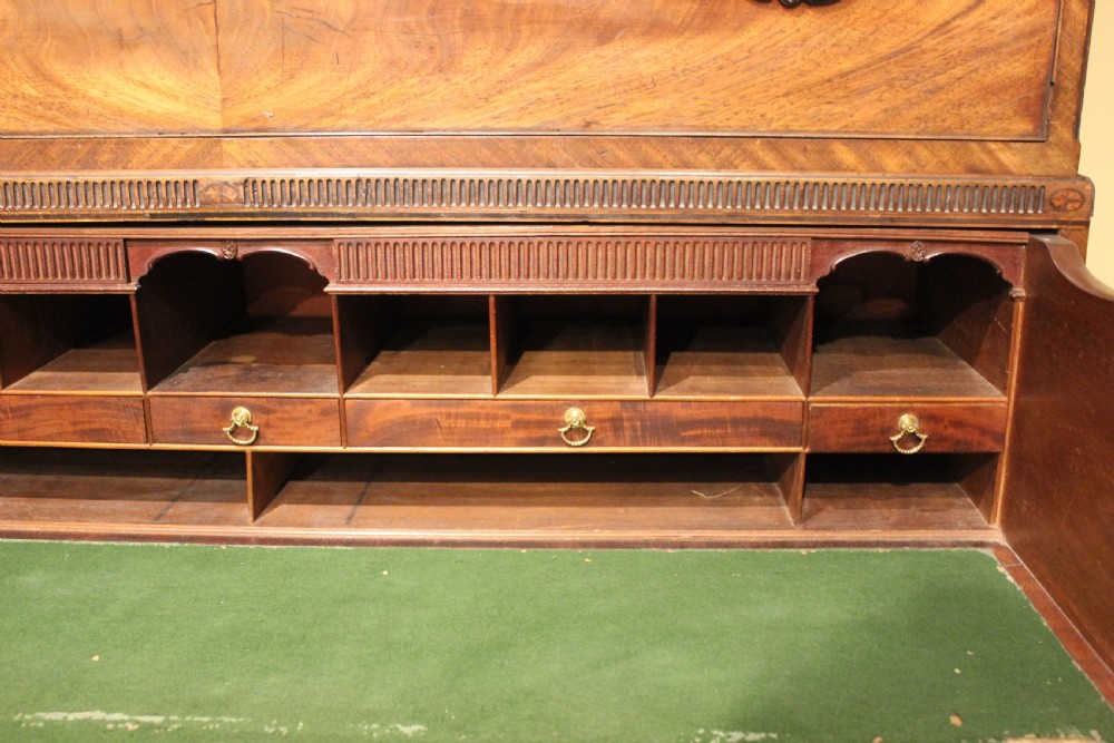 A late 18th-century mahogany secretaire chest on chest featuring flame mahogany veneer, brass swan-neck handles, a decorative blind-fret cornice, and bracket feet. View V