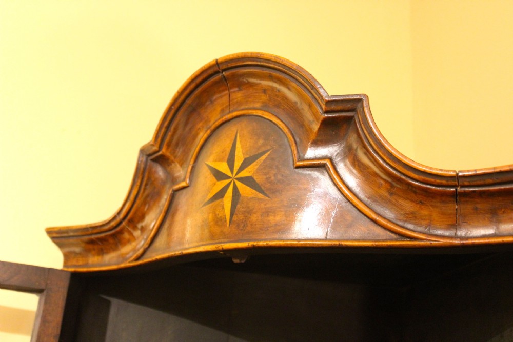 A tall late 19th-century walnut corner cabinet featuring glazed upper doors with geometric glazing bars, an inlaid star motif on the pediment, and solid panelled lower doors. View III