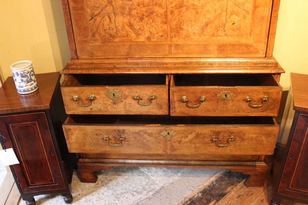 An early eighteenth-century walnut escritoire featuring a fall-front writing upper section with cushion moulding over a chest of three long drawers on bracket feet. View VII