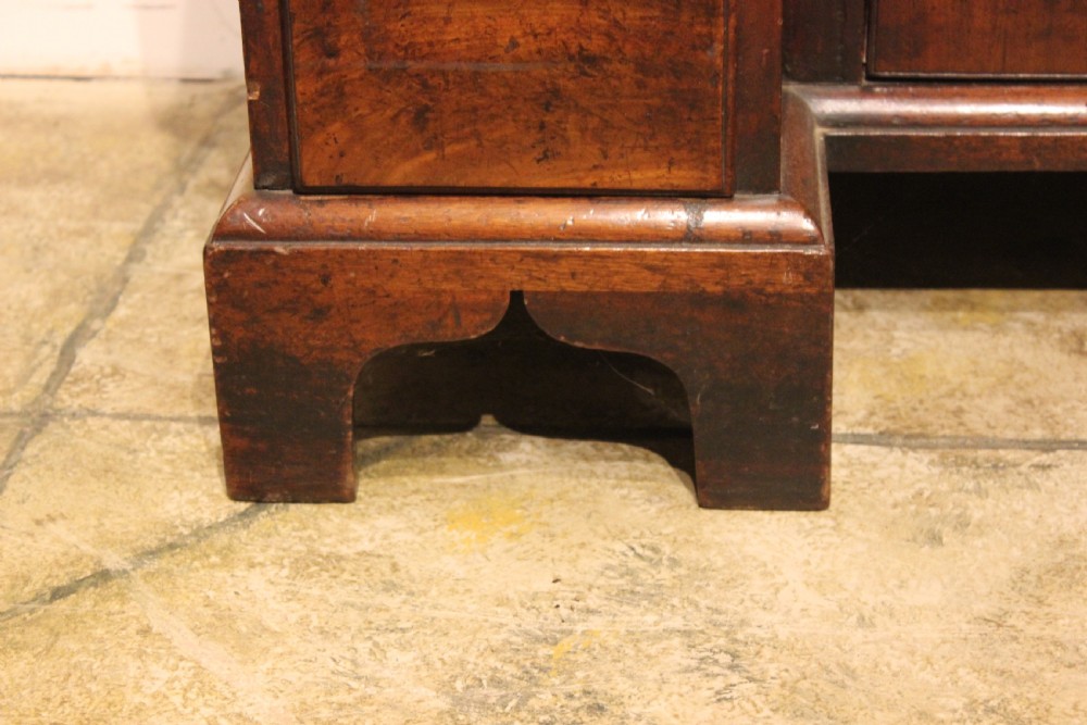 An 18th-century mahogany kneehole desk featuring a long upper drawer, six pedestal drawers, a central cupboard, and brass hardware. View V