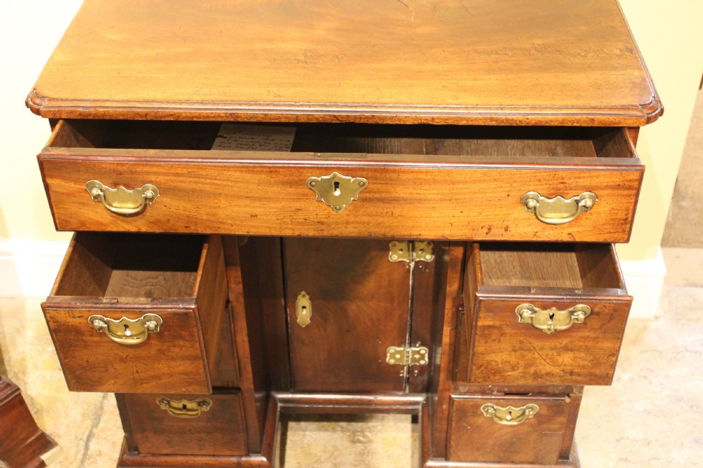 An 18th-century mahogany kneehole desk featuring a long upper drawer, six pedestal drawers, a central cupboard, and brass hardware. View VII