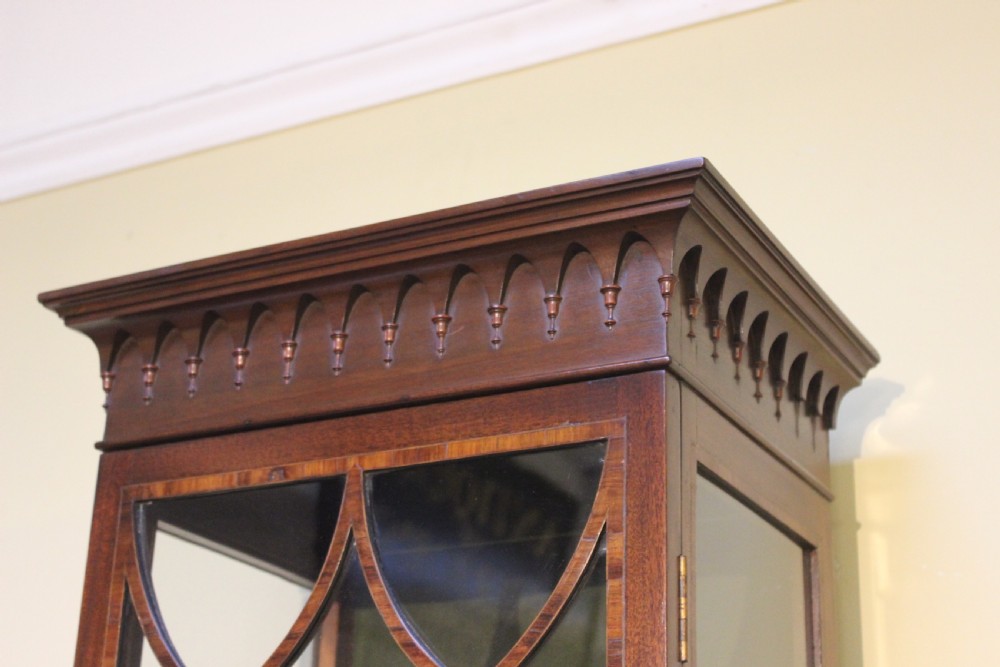 A tall, narrow late 19th-century mahogany display cabinet featuring a single glazed door with Gothic arched glazing bars and a green fabric-lined interior. View III