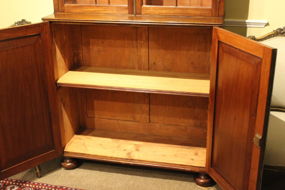 A tall 19th-century mahogany bookcase featuring an upper cabinet with two gothic-arched glazed doors above a lower cupboard base with two flame mahogany panelled doors. View IV